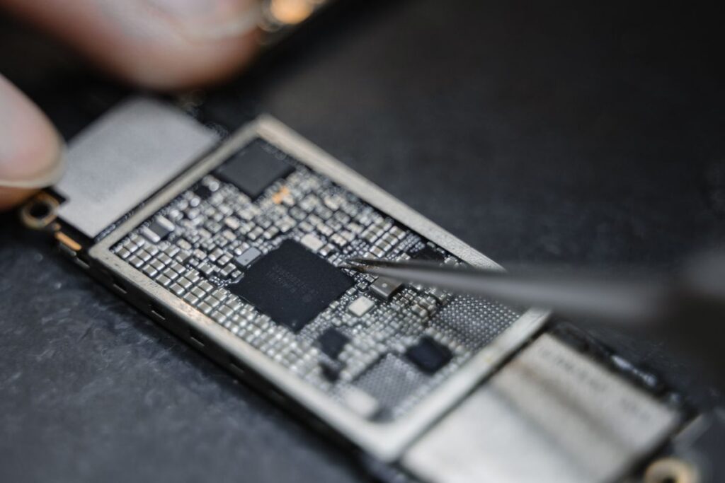 Technician using tweezers to repair an electronic circuit board
